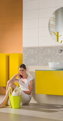 RAKO | Koupelna s lesklým melírovaným tiskem v kombinaci bílé, oranžové a šedé. Jako doplněk dekorované obklady a listely.